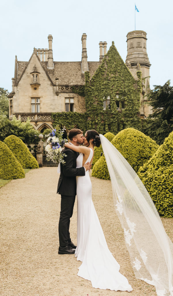 Wedding couple kissing in front of manor house in the spring