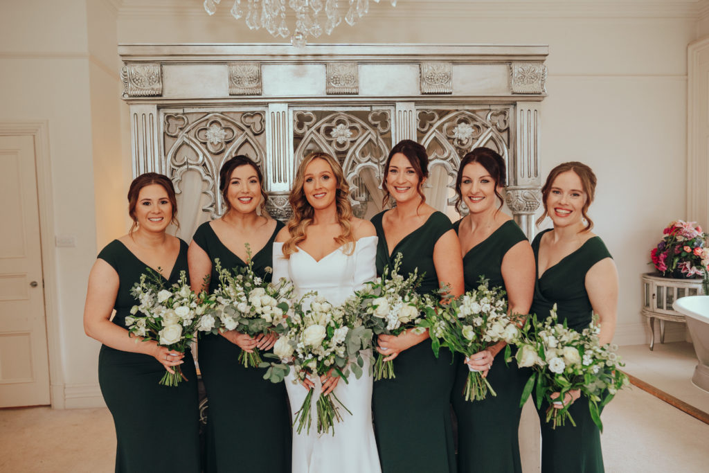 Bride & her bridesmaids in dark green dresses holding bouquets